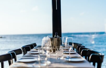 שולחן ערוך עם בקבבוק יין יחד עם כוסות מול הים במסעדת פורט לוקאל ביסטרו