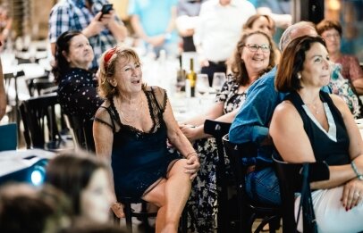 נשים מבוגרות יושבות ונהנות בצפייה באירוע הנערך במסעדת פורט לוקאל ביסטרו